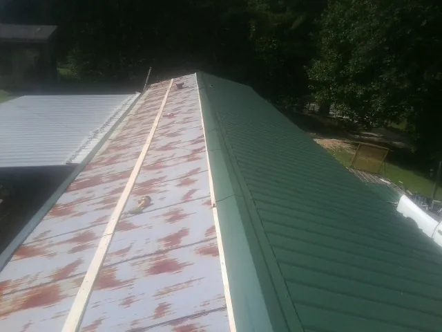 Old rusted panels beside newly installed green metal roofing — Wind Damage Roof Repair by Roofing Brothers in Whitwell