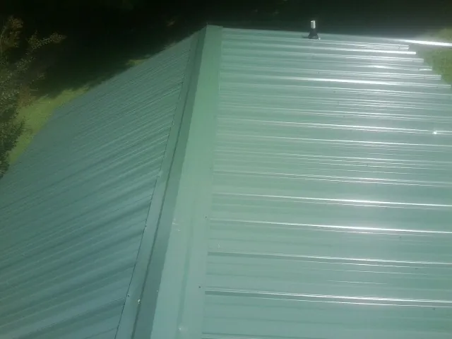 New green metal panels meeting at the ridge of a roof — Flat Roof Repair work by our crew in Whitwell