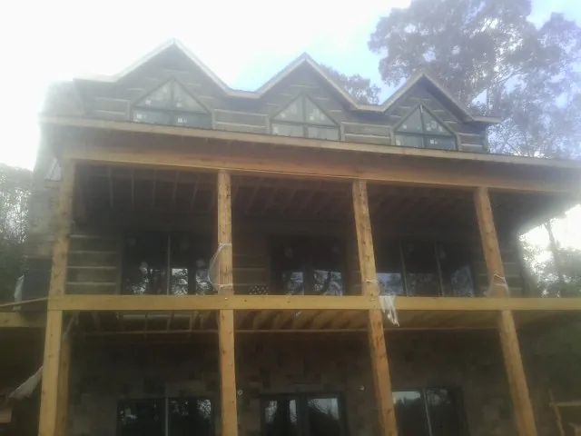 Dormers and porch framing on a large log home under construction — Roof Coating work by our crew in Whitwell