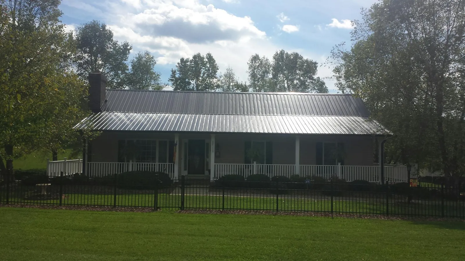 Gray metal roof on a brick ranch with a full width front porch — Gutter Guard Installation work by our crew in Whitwell