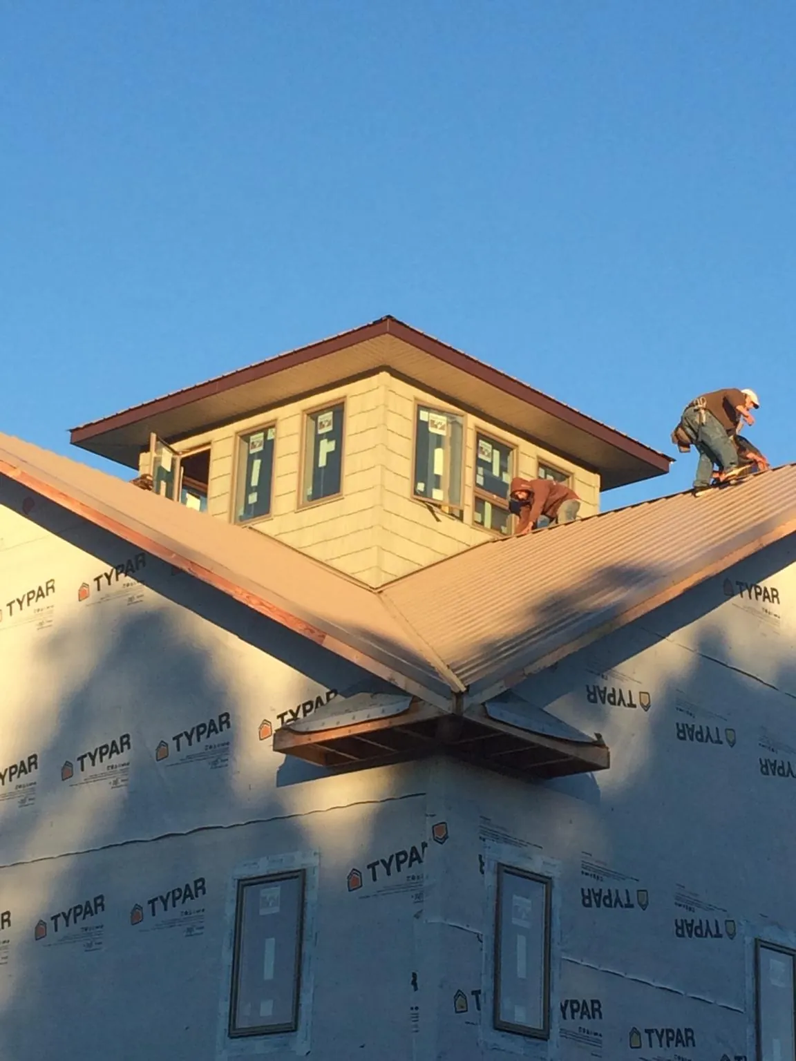 Roofers working around a rooftop cupola on a new metal roof at sunset — Roof Waterproofing in Whitwell by Roofing Brothers
